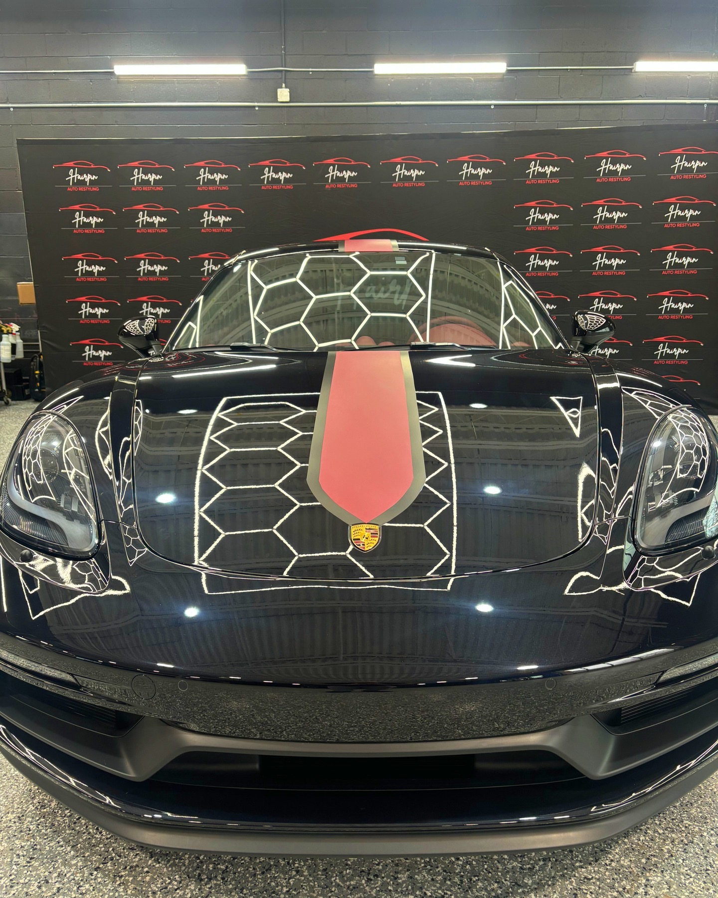 Black Porsche 718 with a red racing stripe in the Hairpin studio